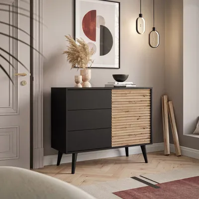 A modern dresser with a slatted wood door is placed in a well-lit room with a large abstract art piece on the wall.