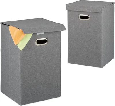 Two grey laundry baskets with lids are shown against a white background. One basket in the foreground has its lid slightly ajar, revealing some folded towels inside. The other basket is in the background.