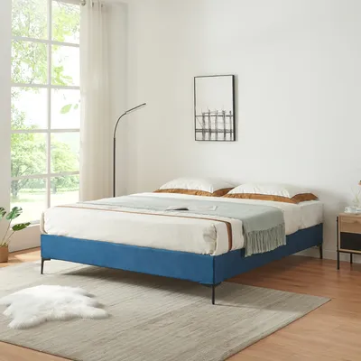 A bedroom scene with a blue bed, rug, and a large window.