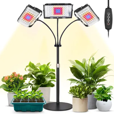 A plant grow light with three adjustable heads is shown illuminating several potted plants and a seedling tray.