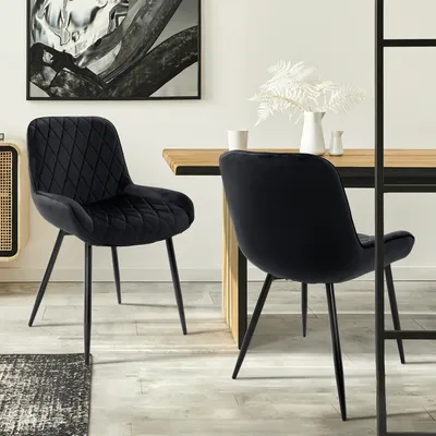Two black velvet dining chairs are shown in a dining room setting.