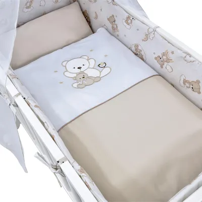 A baby crib set with a white and beige color scheme, featuring teddy bear motifs.