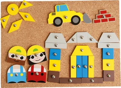 A construction-themed toy set arranged on a corkboard.
