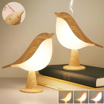 Two bird-shaped lamps are displayed on a surface with books, and a close-up inset shows a finger touching the lamp's head.