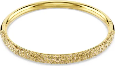 A close-up studio shot of a gold-colored bangle bracelet adorned with small, champagne-colored stones.
