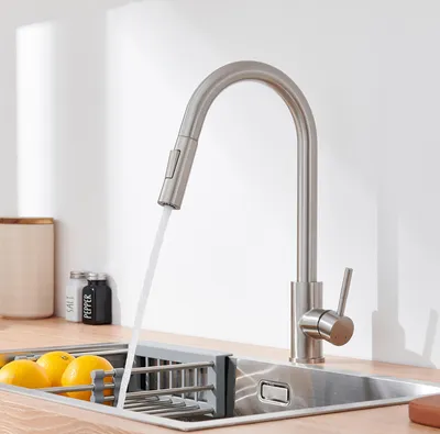 A kitchen sink with a faucet running water into it, and lemons in a drying rack.