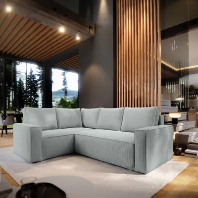 A modern living room with a large L-shaped sectional sofa, large windows with a view of trees and mountains, and wooden architectural elements.