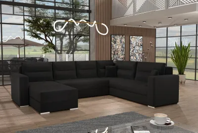 A modern living room with a large black sectional sofa, large windows, and decorative art.
