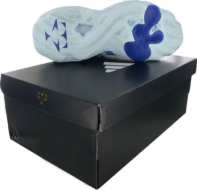 The sole of a light blue basketball shoe rests on top of a black shoe box.