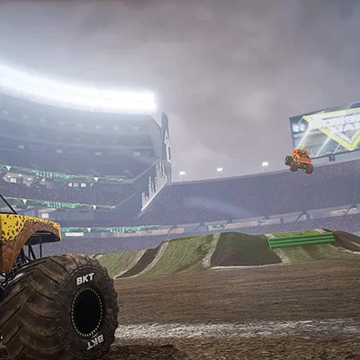 Monster trucks in a stadium during a competition.