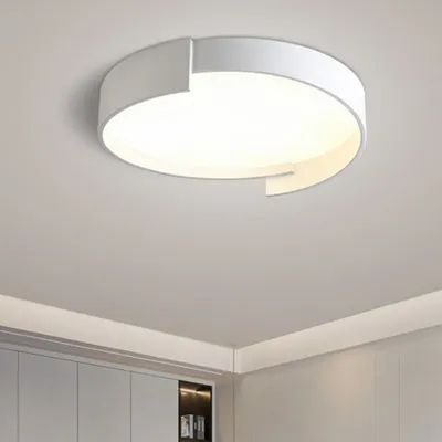 A modern white ceiling light fixture is mounted on a light gray ceiling above a row of white cabinets.
