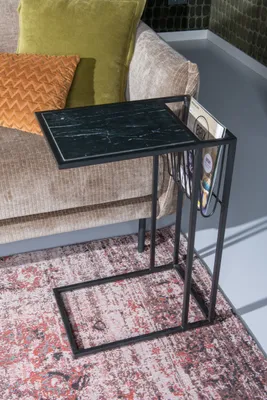 A side table with a marble top and magazine rack next to a sofa with cushions.