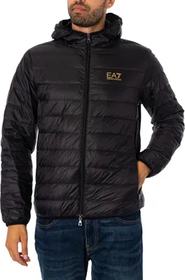 A man wearing a black puffer jacket and blue jeans, posing for a product shot.