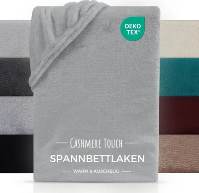 A collection of folded bed sheets in various colors, with a focus on a silver sheet in the foreground. The image includes marketing text and a certification logo.