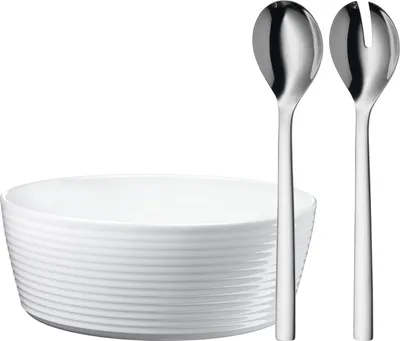 A white salad bowl with two silver serving utensils.
