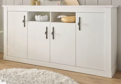 A white sideboard with four doors and two open shelves on top, placed on a wooden floor with a fluffy rug in front.