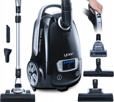 A black Yoer Silent Intense vacuum cleaner with various attachments, displayed against a white background. A hand is shown holding the vacuum cleaner handle.