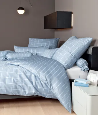 A neatly made bed with blue and white checkered bedding, including pillows and bolster pillows.