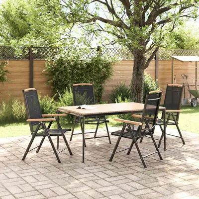 A patio set with four chairs and a table is arranged on a paved patio in a garden setting, under a large tree.