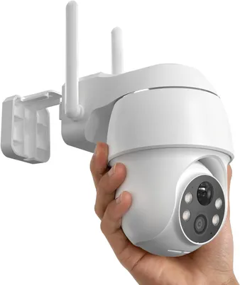 A hand holding a white security camera with two antennas.