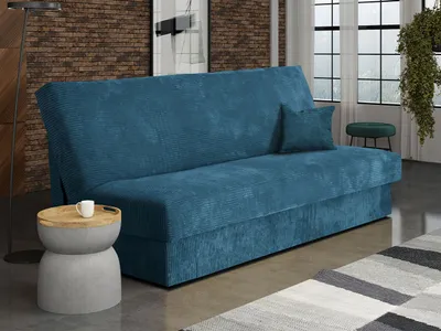 A blue corduroy sofa bed is shown in a living room setting, with a small side table and a rug.
