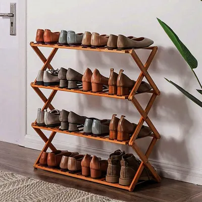 A wooden shoe rack filled with various women's shoes, placed against a white wall.