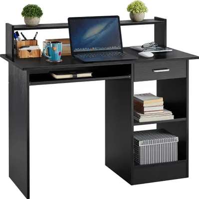 A black computer desk with a laptop, books, and decorative plants.