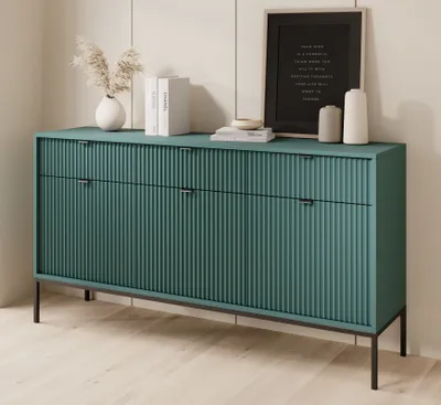 A green sideboard with black legs and black handles is displayed against a white paneled wall.
