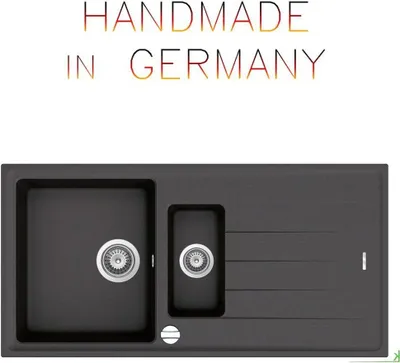 A dark gray granite kitchen sink with two basins and a draining board, with text above indicating it is handmade in Germany.