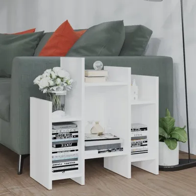 A white shelving unit is placed next to a sofa, with books and decorative items on the shelves.