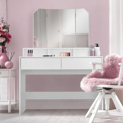 A white vanity table with a tri-fold mirror and pink accents in a room with pink walls.