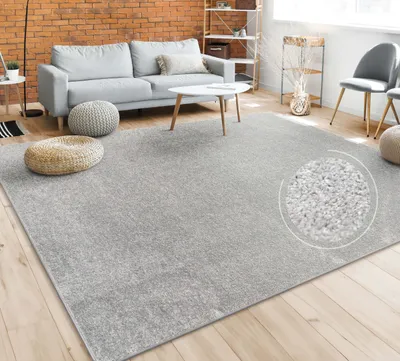 A living room scene with a gray rug, sofa, coffee table, and poufs.