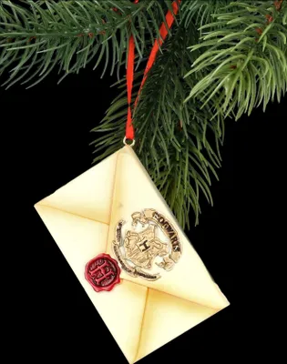 A Harry Potter Hogwarts letter ornament hanging from a Christmas tree branch.