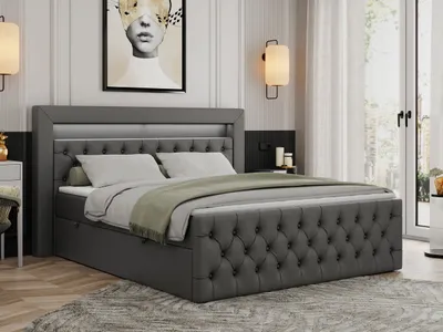 A modern bedroom with a large, dark gray upholstered boxspring bed as the main focus. The bed has a tufted headboard with integrated LED lighting. The room is decorated with a large abstract artwork above the bed and two wall-mounted lamps.
