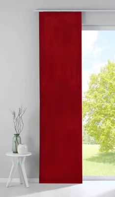A red panel curtain hanging in front of a window with a view of trees and sky.