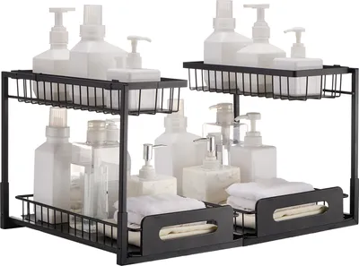 Two black, two-tiered under-sink organizers filled with various bottles and folded towels.