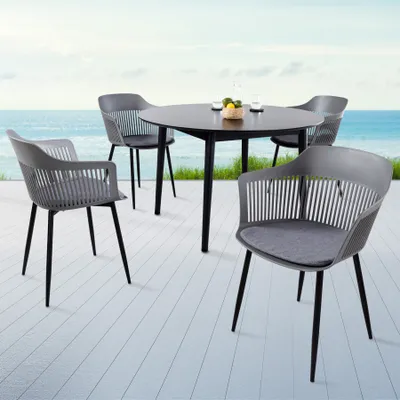 An outdoor dining set with chairs and a table on a deck overlooking the ocean.