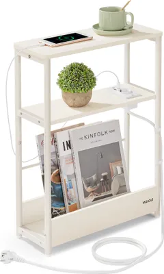 A narrow side table with three shelves, a plant, a cup, a phone, and magazines.