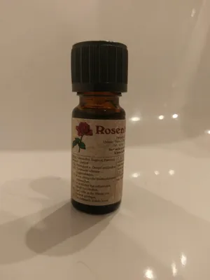 Kleine braune Flasche mit einem schwarzen Verschluss. Auf dem Etikett steht "Rosenblüte".