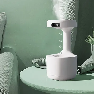 A white humidifier with a digital clock display sits on a light green table next to a green sofa.