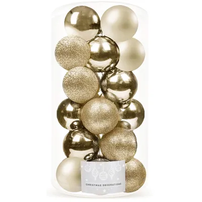 A clear studio shot of a container filled with gold and champagne colored Christmas ornaments.