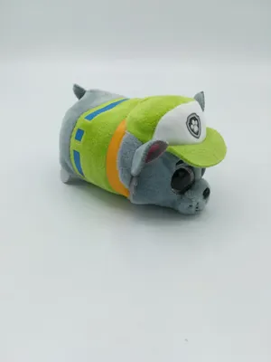 A stuffed toy dog wearing a green vest and hat, set against a white background.