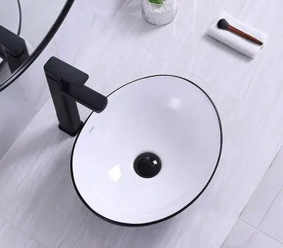 A modern bathroom sink with a black faucet and drain.