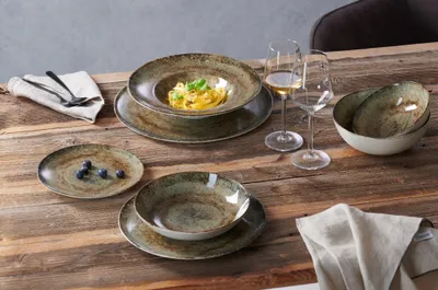A table setting with plates, bowls, and wine glasses.