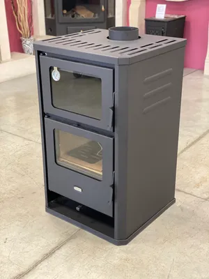A dark gray wood-burning stove with a glass door on a light gray floor.