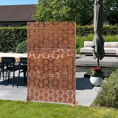 A decorative outdoor screen is set up on a patio next to outdoor furniture and an umbrella.