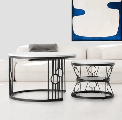 Two round coffee tables with white tops and black metal bases are shown in a living room setting.