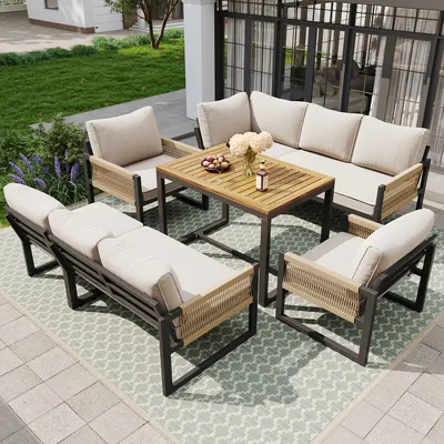 An outdoor patio set with a sofa, chairs, and a coffee table on a patterned rug.