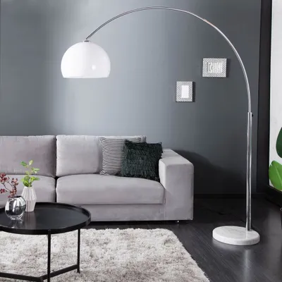 A modern living room with a grey sofa, black coffee table, and a large arc floor lamp.