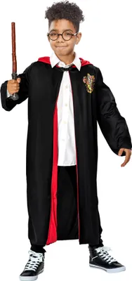 A young boy dressed as Harry Potter stands against a white background, holding a wand.